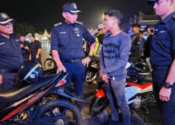 AHMAD Dzaffir Mohd. Yussof ketika melakukan pemeriksaan ke atas motosikal yang ditutup nombor pendaftarannya oleh seorang remaja pada Op Khas Samseng Jalanan di Plaza Tol Senawang, Seremban, semalam.-UTUSAN/NOR AINNA HAMZAH.