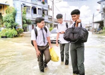 MOHD. Rais Takiyuddin (kanan) bersama rakannya meredah banjir untuk pulang ke rumah apabila jalan ke Sekolah Menengah Kebangsaan Rantau Panjang, Kelantan, dinaiki air. - UTUSAN/ROHANA ISMAIL