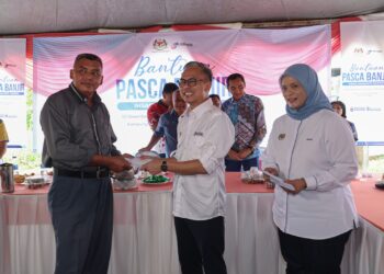 FAHMIFadzil (tengah) menyampaikan Bantuan Pasca Banjir kepada pengamal media yang terjejas banjir di Kuala Terengganu hari ini. -  UTUSAN/PUQTRA HAIRRY