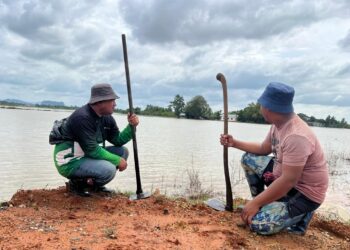 DUA pesawah hanya mampu termenung melihat keadaan sawah ditenggelami air di Kampung Bakong, Arau, Perlis.-UTUSAN/MOHD. HAFIZ ABD. MUTALIB