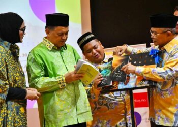 MOHD. Arifin Mohd. Arif (dua kiri) melihat salah sebuah karya yang memenangi Hadiah Puisi K. Bali di DBP Sabah di Kota Kinabalu, semalam.
