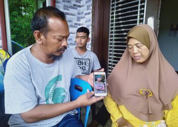 AHMAD Tarmizi Safar menunjukkan gambar anaknya, Ahmad Zulhilmi sambil diperhatikan Zuraida Abu Bakar semasa ditemui di rumah mereka di Kampung Padang Limau, Kota Kuala Muda di Sungai Petani.