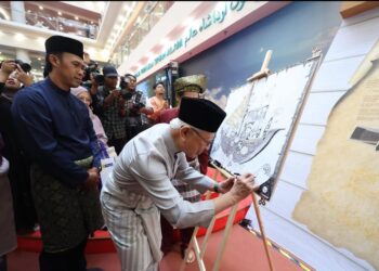 RAJA Arshad menurunkan tandatangan pada lukisan bahtera semasa perasmian pameran itu di Shah Alam bar-baru ini. – UTUSAN/ABD RAZAK IDRIS