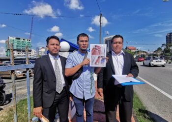 MUHAMMAD Syarifuddin Manan (tengah) menunjukkan laporan polis dan gambar kecederaan bayinya di Ibu Pejabat Polis  Kuala Terengganu. - UTUSAN/ KAMALIZA KAMARUDDIN