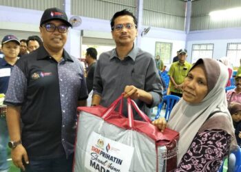 M. SHANMUGAM (kiri) menyampaikan sumbangan kepada seorang mangsa banjir di Tangkak.