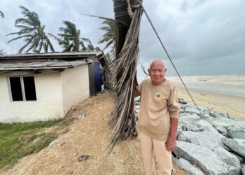 SEORANG penduduk membaiki susunan daun kelapa bagi menghadang tiupan angin kencang di Pantai Damak, Bachok, Kelantan. - UTUSAN/TOREK SULONG