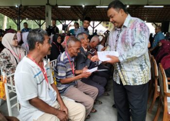 AZMAIN Abidin menyampaikan bantuan sekali beri kepada salah seorang penerima di Tanah Merah, Kelantan-UTUSAN/ROHANA ISMAIL.
