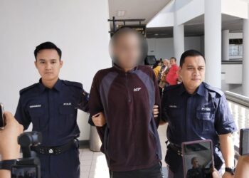 TERTUDUH diiringi anggota polis ketika dihadapkan ke Mahkamah Majistret Ayer Keroh, Melaka.