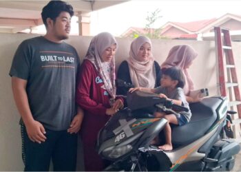 FARIDAH Abdul Karim (dua, kiri) dan anak-anaknya melihat keadaan motosikal yang ditunggang suaminya ketika ditemui di Kampung Mak Chili, Kemaman, Terengganu. – UTUSAN/NIK NUR IZZATUL HAZWANI NIK ADNAN