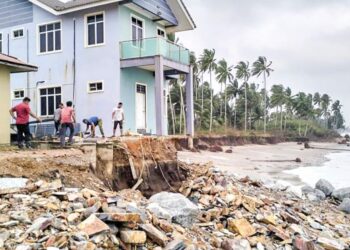PENDUDUK bergotong-royong menambak pasir untuk mengurangkan kesan hakisan di Kampung Tanjung Batu Rakit, Kuala Nerus, Terengganu. – UTUSAN/KAMALIZA KAMARUDDIN
