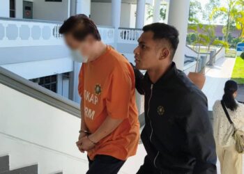 SUSPEK diiringi pegawai SPRM ketika hadir ke Kompleks Mahkamah Ayer Keroh, Melaka bagi mendapatkan perintah reman. - UTUSAN/MUHAMMAD SHAHIZAM TAZALI