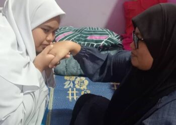 ROSMAYANI RUSTAM bersalaman dengan ibu saudaranya Rafeah Samat yang menggantikan ibunya untuk mendapat restu sebelum masuk ke dewan peperiksaan Sijil Peperiksaan Malaysia (SPM) di Sekolah Menengah Kebangsaan (SMK) Kahang.