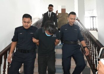 TERTUDUH diiringi anggota polis ketika dihadapkan ke Mahkamah Sesyen Ayer Keroh, Melaka.