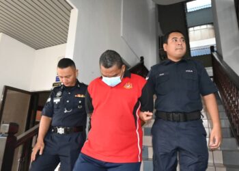 TERTUDUH diiringi anggota polis ketika dihadapkan ke Mahkamah Sesyen Ayer Keroh, Melaka.