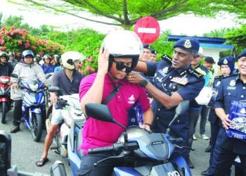 M. Kumar memakaikan topi keledar kepada seorang penunggang motosikal pada Program Advokasi Keselamatan Jalan Raya PDRM Bersama Perkeso sempena OP Selamat Tahun Baru Cina di Plaza Tol Kempas, Johor Bahru. - UTUSAN/RAJA JAAFAR ALI