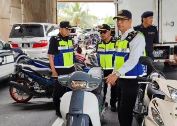 MOHAMMAD Yusoff Abustan memeriksa motosikal yang disita dalam operasi khas sempena Tahun Baharu Cina di Jalan Tambun, Ipoh hari ini. - UTUSAN