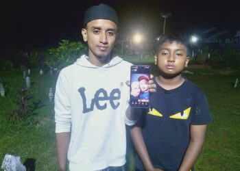 MOHD. Danial Ikmal bersama adiknya, Mohd. Danial Irfan menunjukkan gambar ibu bapa mereka yang maut nahas di Thailand selepas dikebumikan di Tanah Perkuburan Islam Masjid Darul 'Ulum Merbau Pulas, Kulim.