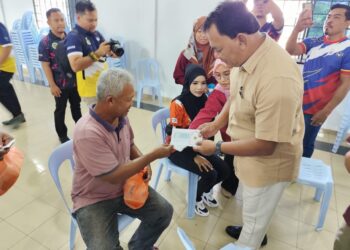 RAHMAD Mariman menyampaikan sumbangan zakat fitrah kepada seorang penerima di Ayer Molek, Melaka. - UTUSAN/AMRAN MULUP