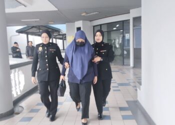 TERTUDUH diiringi anggota SPRM ketika dihadapkan ke Mahkamah Sesyen, Ayer Keroh, Melaka atas pertuduhan meminta dan menerima suapan. - UTUSAN/MUHAMMAD SHAHIZAM TAZALI