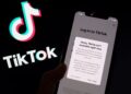 FOTO menunjukkan aplikasi TikTok pada skrin telefon pintar di hadapan logo aplikasi video popular milik China itu.- AFP