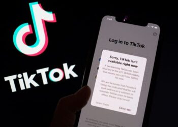 FOTO menunjukkan aplikasi TikTok pada skrin telefon pintar di hadapan logo aplikasi video popular milik China itu.- AFP