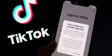 FOTO menunjukkan aplikasi TikTok pada skrin telefon pintar di hadapan logo aplikasi video popular milik China itu.- AFP