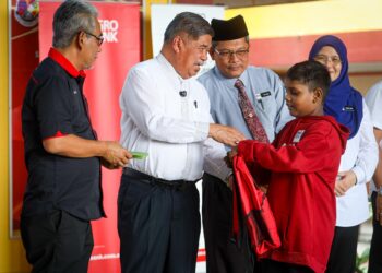 MOHAMAD Sabu menyampaikan sumbangan kepada seorang murid di SMK Jalan Kebun, Shah Alam, Selangor hari ini-UTUSAN/ SADDAM YUSOFF