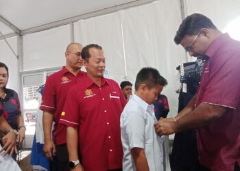S. VEERAPAN memakaikan baju sekolah kepada kanak-kanak yang hadir pada Program Jualan Rahmah Madani Kembali ke Sekolah Peringkat Negeri Sembilan 2025 di Dataran Centrio, Seremban 2, Seremban hari ini. - UTUSAN /NUR SHARIEZA ISMAIL
