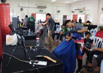 TUKANG gunting rambut melayan kanak-kanak yang tidak melepaskan peluang menyertai aktiviti potong rambut percuma dekat Dewan Pinang Majlis Bandaraya Shah Alam (MBSA), di Shah Alam, Selangor. - UTUSAN/MOHAMAD NAUFAL MOHAMAD IDRIS