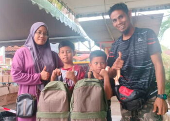 MOHD. Zikir Ahmad Rodhwan Abdul (kanan) dan isterinya bersama  dua anak mereka menerima sumbangan pakaian seragam dan peralatan sekolah di Sekolah Menengah Kebangsaan Seri Tualang Temerloh di Temerloh, Pahang. – UTUSAN/HARIS FADILAH AHMAD