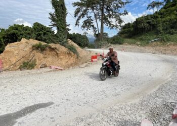 PENDUDUK tempatan dan pengguna jalan raya menggunakan jalan sementara yang strukturnya diperbuat daripada batu selepas jalan di Kilometer 35 Jalan Gua Musang-Jeli runtuh. – UTUSAN/AIMUNI TUAN LAH