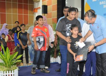 MOHD. Jafni Md Syukor menyampaikan peralatan sekolah kepada salah penerima pada majlis Penyerahan Sumbangan Back To School Bagi Anak Yatim dan Miskin Bandar Sesi Persekolahan Tahun 2025 di Dewan Raya Putra, Bandar Putra Kulai, Johor.-UTUSAN/RAJA JAAFAR ALI