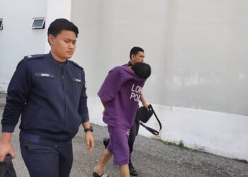 TERTUDUH (tengah) semasa dibawa oleh polis untuk menghadiri prosiding perbicaraan berkait kes amang seksual fizikal terhadap seorang remaja di Mahkamah Sesyen Kota Bharu, Kelantan hari ini.UTUSAN/ROSALWANI CHE SOH.