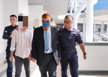 TERTUDUH (dua dari kanan) diiringi anggota polis ketika dihadapkan ke Mahkamah Majistret Ayer Keroh, Melaka.- UTUSAN/MUHAMMAD SHAHIZAM TAZALI