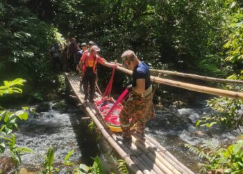 PASUKAN penyelamat membawa keluar wanita Orang Asli yang cedera dipatuk ular untuk dirawat dari Kampung Lenweng, Pos Kemar di Gerik hari ini. - UTUSAN/IHSAN JBPM PERAK