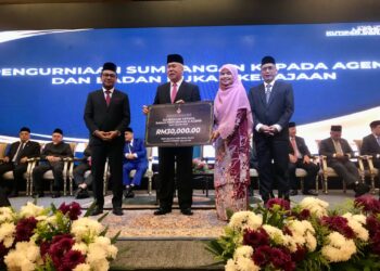 TENGKU Mohamad Rizam Tengku Abdul Aziz (dua dari kiri) menyampaikan replika cek bagi bantuan sumbangan kepada wakil Badan Pertubuhan dan Agensi, Datin Wan Nor Hanita Wan Yaacob sempena Laporan Khas Kutipan Zakat dan Agihan Zakat Maik Bagi Tahun 2024 di Kota Bharu, Kelantan. - UTUSAN/ ROSLIZA MOHAMED