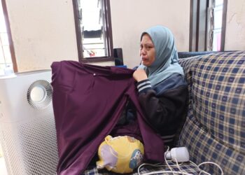 NOR Hafizah Mohd. Sheriff sebak ketika menunjukkan baju Melayu yang dibeli buat arwah suaminya yang meninggal dunia dalam kemalangan jalan raya, kelmarin. – UTUSAN/NOR AINNA HAMZAH