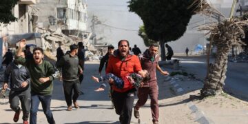 SEORANG lelaki berlari sambil mendukung kanak-kanak perempuan yang cedera akibat bedilan udara tentera Israel di Gaza City, Palestin. – AFP