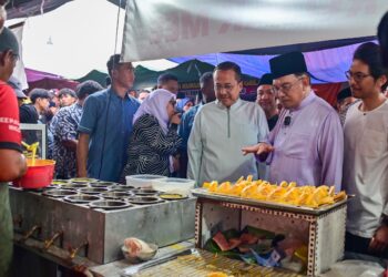 ANWAR Ibrahim (dua dari kanan) dan Ahmad Samsuri Mokhtar (tiga dari kanan) menyantuni para peniaga dan pengunjung semasa melawat Bazar Ramadan Jalan Padang Astaka di Kemaman, Terengganu, hari ini. - UTUSAN/PUQTRA HAIRRY