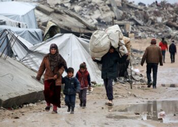 PENDUDUK Palestin berjalan membawa barangan ketika melarikan diri akibat serangan Israel di Beit Lahia, utara Gaza, kelmarin.- AFP