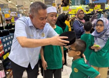 MOHAMED NAZARI Noordin menyantuni salah seorang penerima semasa program membeli-belah di Mydin Mall, Subang Jaya, semalam.