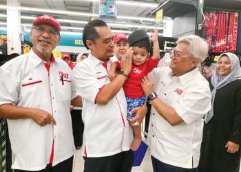 NIK Izani Nik Ibrahim (kanan) memakaikan songkok kepada kanak-kanak yang juga penerima sumbanga pada Program Shopping Raya di sebuah pasar raya di Kota Bharu, Kelantan. – MINGGUAN/ROSLIZA MOHAMED