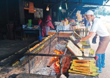 PENIAGA membakar lemang di gerainya di Kijal, Kemaman, Terengganu. – UTUSAN/NIK NUR IZZATUL HAZWANI NIK ADNAN