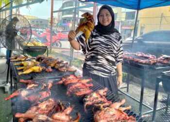 SAIDATUL Fatihah Muhammad menunjukkan ayam panggang yang dijual pada harga RM18 di Jalan Sultan Zainal Abidin, Kuala Terengganu semalam. – MINGGUAN/KAMALIZA KAMARUDDIN