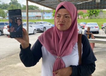 HASLINDA Jupri menunjukkan gambar dua anaknya yang terlibat dalam kemalangan maut di Jalan Persiaran Senawang 1, Senawang, Seremban Khamis lalu.-UTUSAN/NOR SHAFAWATI YUP.