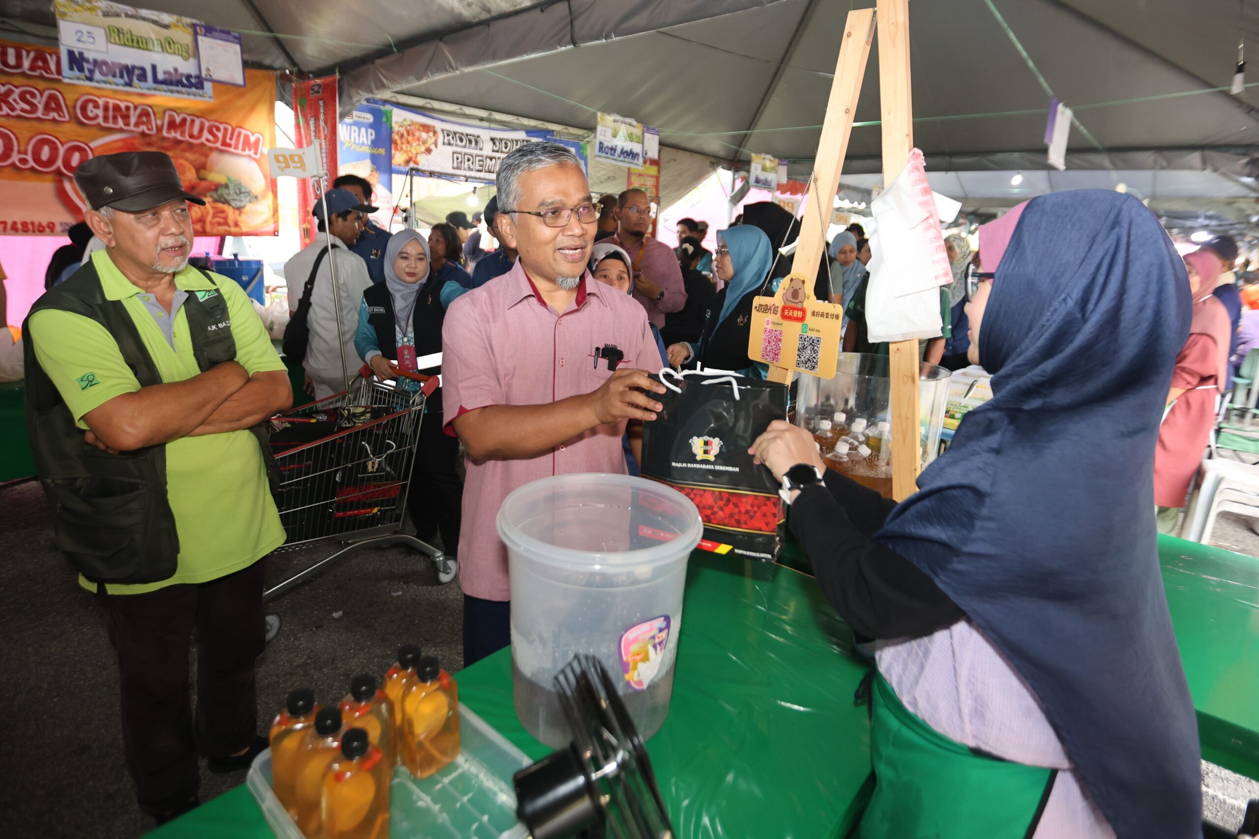 MASRI Razali (tengah) berbual dengan peniaga dan pengunjung Bazar Ramadan One Avenue, Seremban 2, Seremban, semalam. -UTUSAN /NUR SHARIEZA ISMAIL