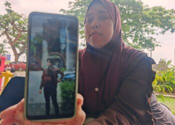 JAMILAH Kamaldin menunjukkan gambar anaknya, Allahyarham Muhammad Syabil ketika ditemui di perkarangan Jabatan Forensik Hospital Melaka hari ini.-UTUSAN/AMRAN ALI