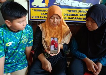ROKIAH Shaari (tengah) menunjukkan gambar terakhir Intan Suraya Zaidi dan Lokman Hakim kepada dua cucunya, Iman Firdaus (kiri) dan anak angkat pasangan itu, Shazwani Abdul Rahman di Kampung Charuk Pelanduk, Sik, Kedah hari ini.