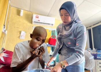 NORANISHA Idayu Sahidan (kanan) membantu menguruskan anaknya, Amier Azrulz Addey Mohd. Tajuddin yang mengidap kanser tulang rahang tahap empat di kediaman mereka di Kampung Telok, Jalan Kuala Perlis-Changlun, Kangar, Perlis semalam. -UTUSAN/ASYRAF MUHAMMAD