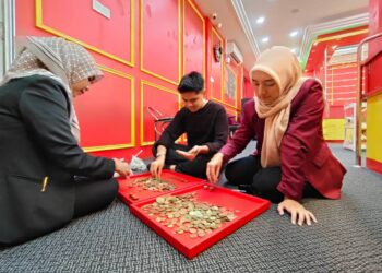 KAKITANGAN MZ Gold Sdn.Bhd giat mengira duit syiling yang digunakan untuk membeli barang kemas di Kota Bharu, Kelantan.-UTUSAN/YATIMIN ABDULLAH.